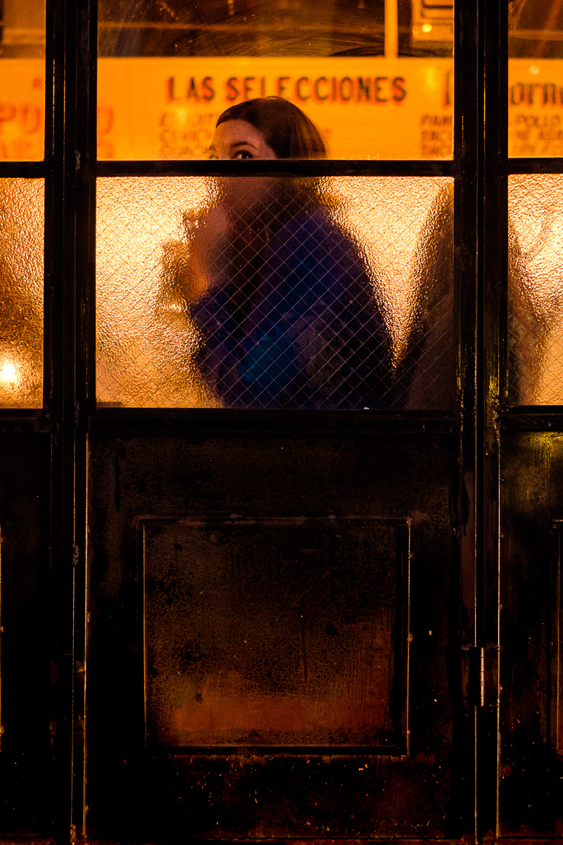 A man in a red bowler hat and checked waistcoat seen from behind between twisted gold poles