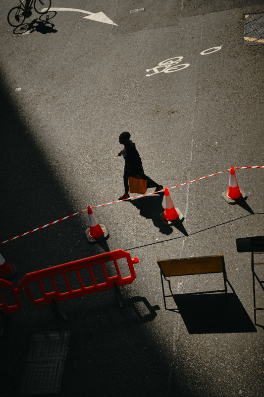 A man on the phone walks towards a car outside a neon-lit club sign reading Tables & Dancing at night