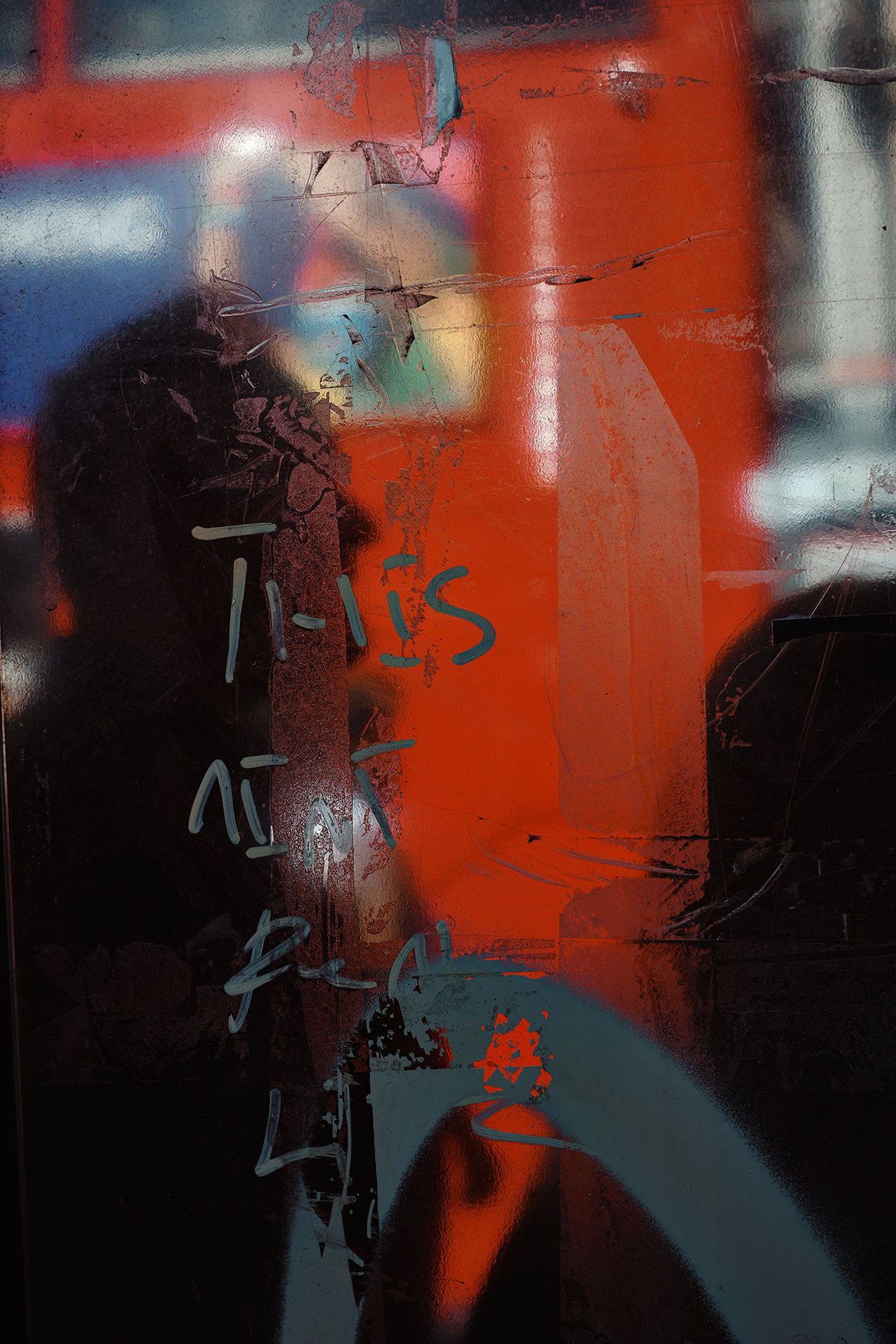 A man bends towards a red wall, his shadow stretched across it in low sunlight