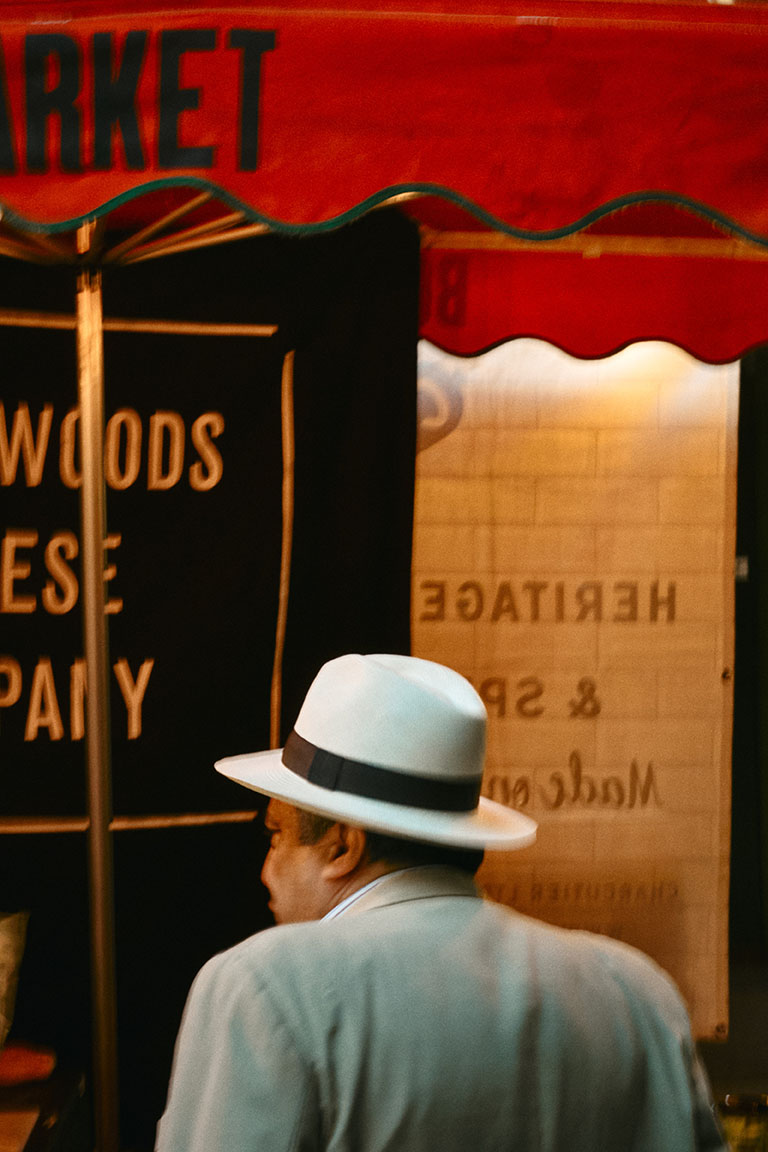 A man on the phone walks towards a car outside a neon-lit club sign reading Tables & Dancing at night