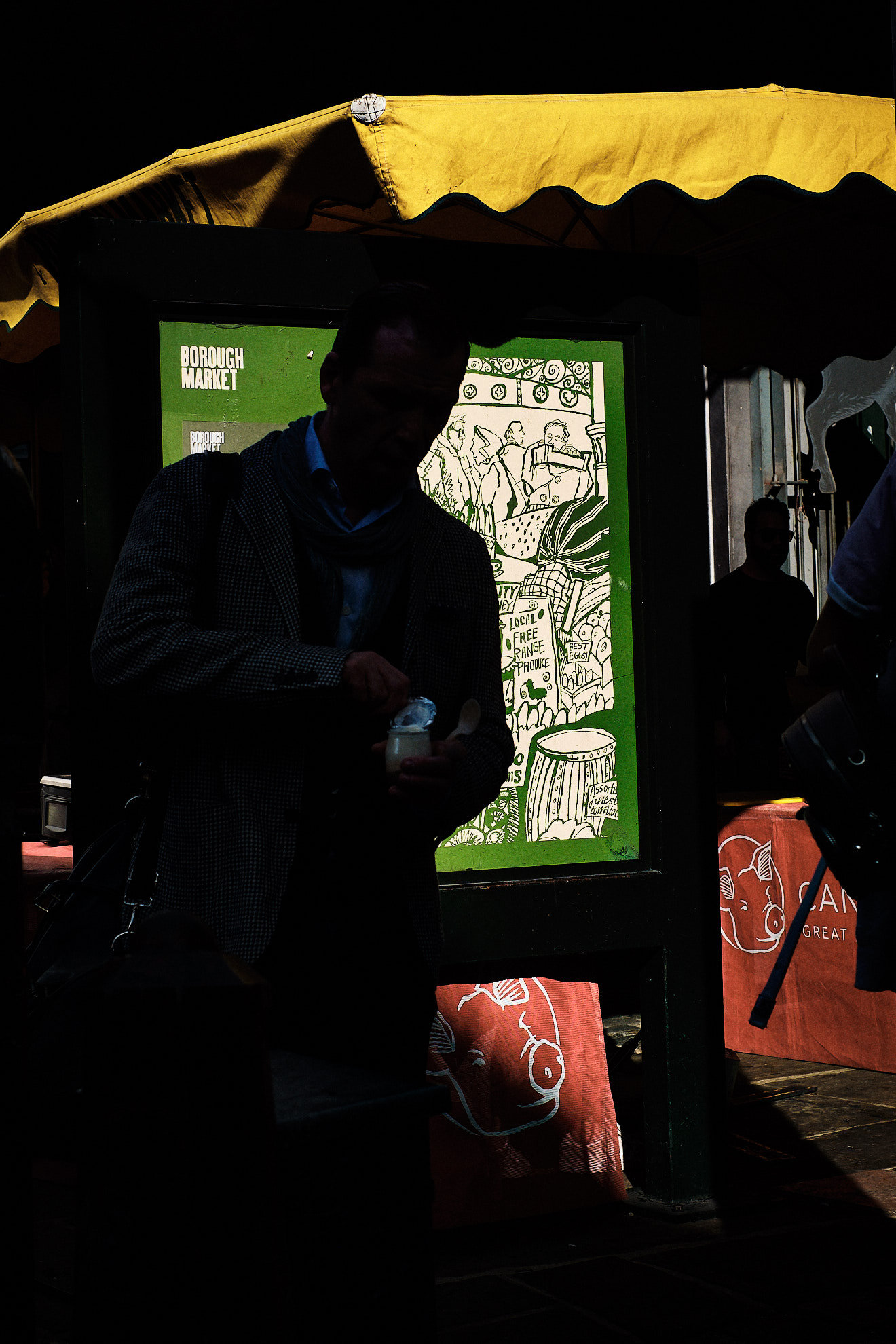A man on the phone walks towards a car outside a neon-lit club sign reading Tables & Dancing at night