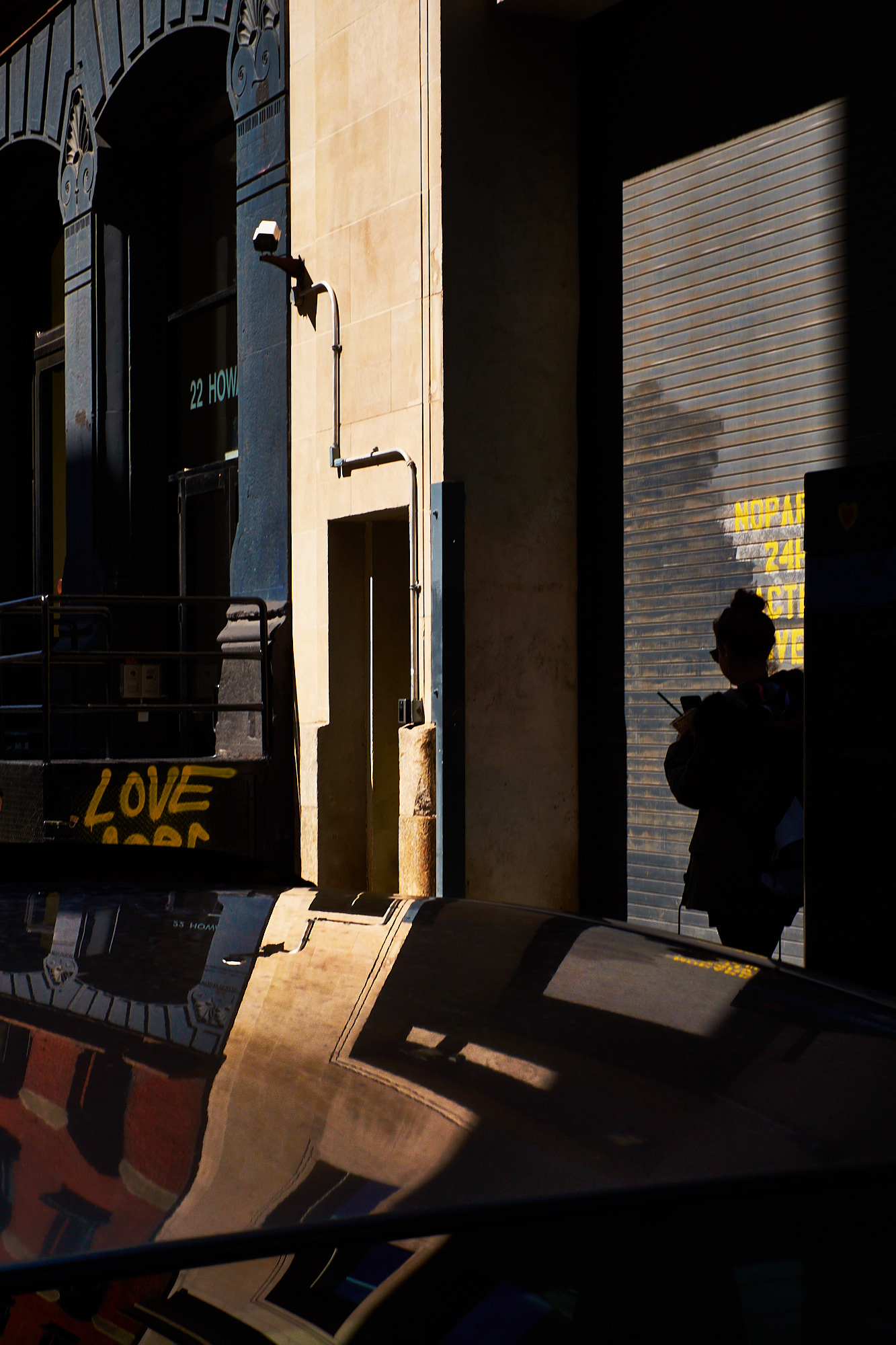 A man on the phone walks towards a car outside a neon-lit club sign reading Tables & Dancing at night