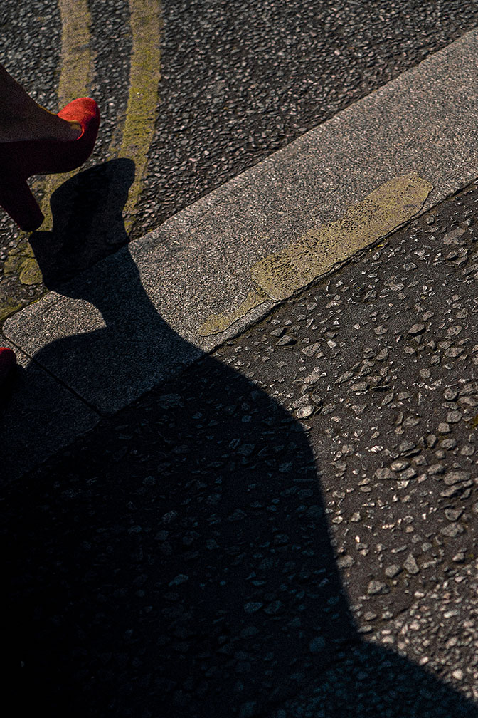 The shadow of a head cast onto a blue tarpaulin, a silhouetted man in a cap at the left edge